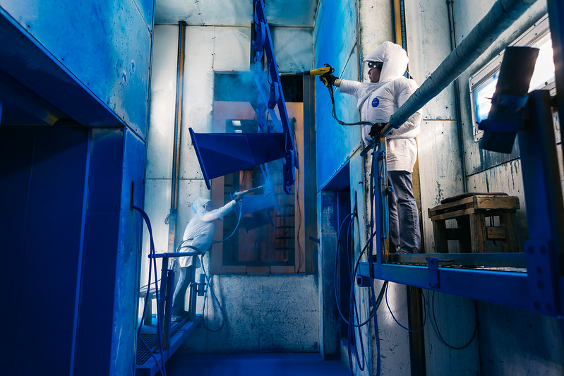 Two manufacturing workers painting equipment.